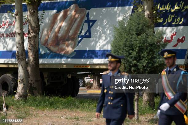 Two members of the Iranian Army's air force are walking past a massive anti-Israeli billboard after a military parade marking the anniversary of...