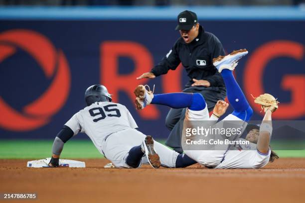 Bo Bichette of the Toronto Blue Jays rolls over after missing the tag on Oswaldo Cabrera of the New York Yankees at second base in the fifth inning...