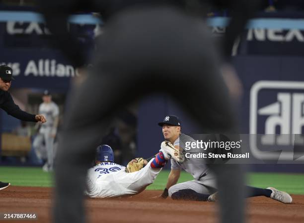 Toronto Blue Jays outfielder Kevin Kiermaier gets tagged out by New York Yankees shortstop Anthony Volpe trying to stretch a single into a double as...