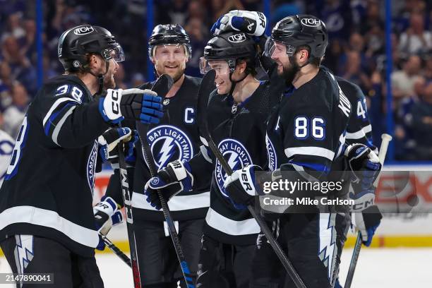 Nikita Kucherov of the Tampa Bay Lightning, right, celebrates his 100th assist on the season with Brayden Point, Brandon Hagel and Steven Stamkos...