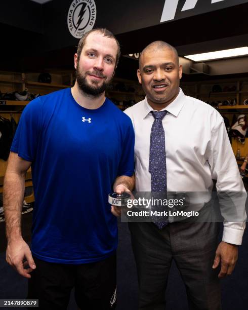 Nikita Kucherov of the Tampa Bay Lightning and video coach Nigel Kirwan pose with his 100th assist puck after the win against the Toronto Maple Leafs...