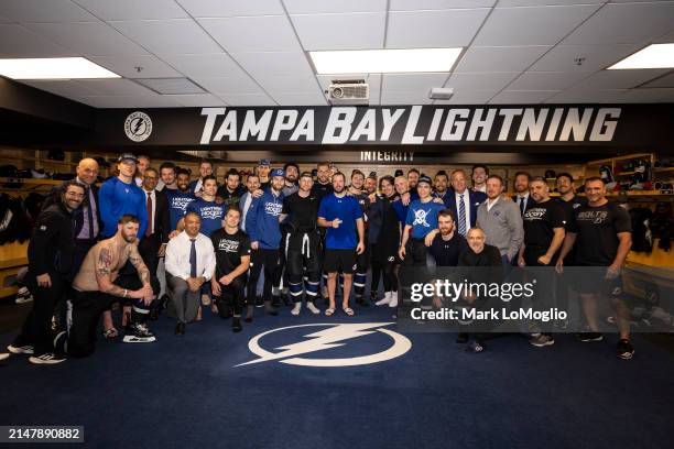 The Tampa Bay Lightning pose with teammate Nikita Kucherov and his 100th assist puck after the win against the Toronto Maple Leafs during the third...