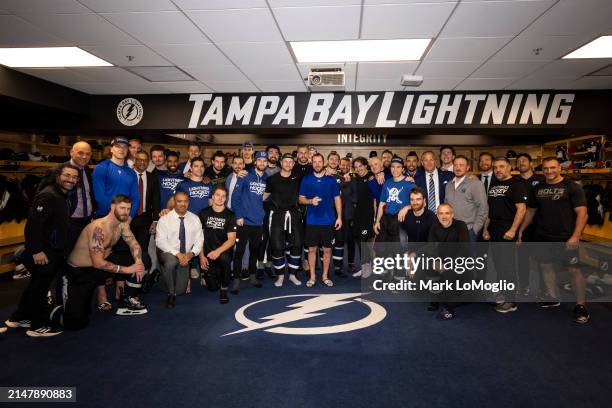 The Tampa Bay Lightning pose with teammate Nikita Kucherov and his 100th assist puck after the win against the Toronto Maple Leafs during the third...