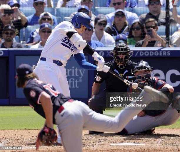 Shohei Ohtani of the Los Angeles Dodgers hits a single against Washington Nationals pitcher Hunter Harvey in the eighth inning of a baseball game on...