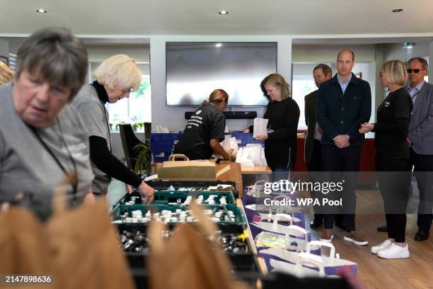 Prince William, Prince of Wales watches as toiletries are packed while speaking to Claire Hopkins, Operations Director during a visit to Surplus to...