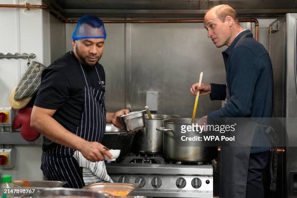 Prince William, Prince of Wales helps make bolognese sauce with head chef Mario Confait, during a visit to Surplus to Supper, in Sunbury-on-Thames on...