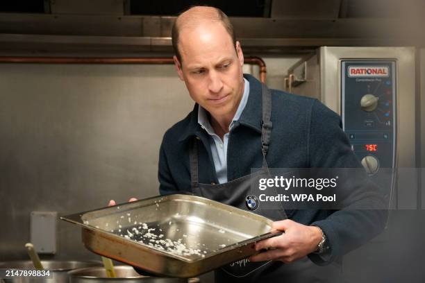 Prince William, Prince of Wales helps make bolognese sauce with head chef Mario Confait, during a visit to Surplus to Supper, in Sunbury-on-Thames on...