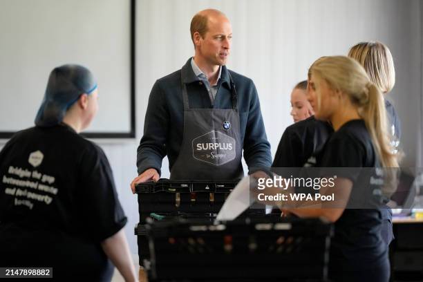 Prince William, Prince of Wales helps sort out food items for distribution during a visit to Surplus to Supper, in Sunbury-on-Thames on April 18,...