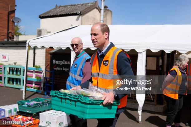 Prince William, Prince of Wales helps to load trays of food into vans during a visit to Surplus to Supper, in Sunbury-on-Thames on April 18, 2024 in...