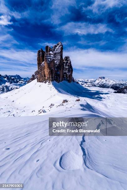 Snowdrift creating artful structures in Tre Cime Natural Park in winter, the summits of Tre Cime di Lavaredo in the distance, seen from Forcella...