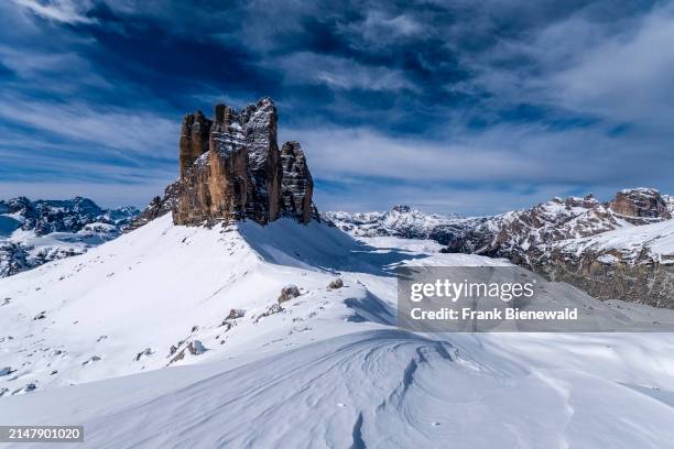 Snowdrift creating artful structures in Tre Cime Natural Park in winter, the summits of Tre Cime di Lavaredo in the distance, seen from Forcella...