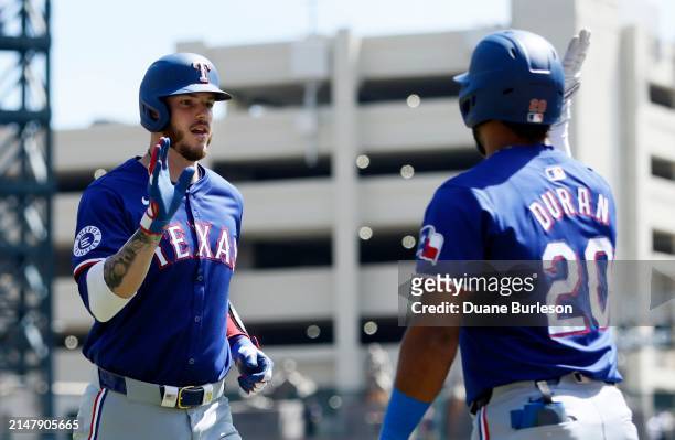 Jonah Heim of the Texas Rangers celebrates with Ezequiel Duran after hitting a two-run home run against the Detroit Tigers during the second inning...