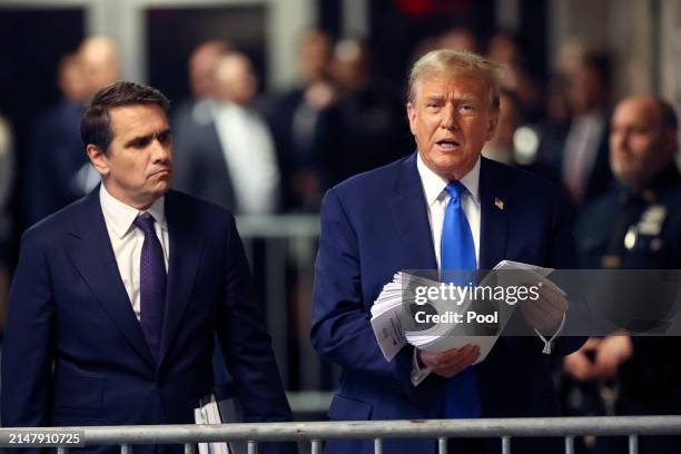 Former US President Donald Trump speaks to the media holding news clippings as he leaves court for the day at Manhattan Criminal Court on April 18,...