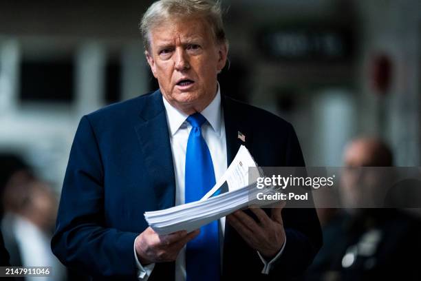 Republican presidential candidate, former President Donald Trump holds print outs of news stories as he speaks to reporters at the end of the day as...