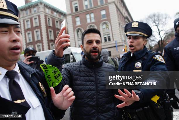 Officers remove a man as pro-Palestinian protesters march outside Columbia University in New York City on April 18, 2024. Officers cleared out a...