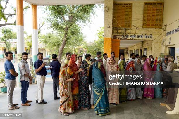 People stand in a queue to cast their votes during the first phase of India's general election at a polling station in Parbatsar, Nagaur District, in...