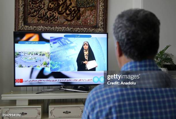 Man watches tv reporter in Tehran, Iran after Iranian official TV confirms 'massive explosions' in central Isfahan province, as US officials confirm...