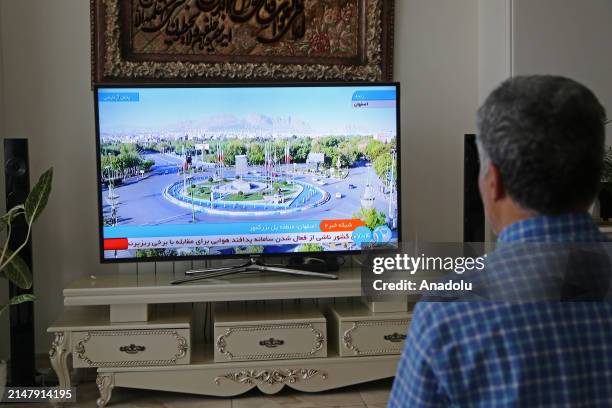 Man watches tv reporter in Tehran, Iran after Iranian official TV confirms 'massive explosions' in central Isfahan province, as US officials confirm...