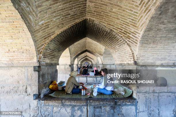 People gather for a picnic under the Si-o-Se Pol Bridge in Iran's central city of Isfahan on April 19, 2024. World leaders appealed for calm on April...