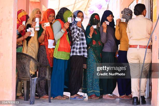 Women are standing in a queue and showing their ID cards as they prepare to cast their votes for the first phase of the Lok Sabha elections in...