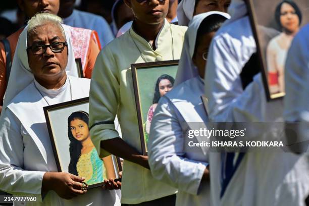 Catholic nuns carry photos as they pay tribute to the victims killed in the 2019 Easter Sunday bombings, at Katuwapitiya St. Sebastian's Church in...