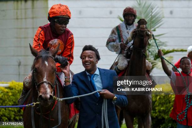 Apprentice jockey Michael Fundi discusses his win with trainer Tony Kuria after winning the Lord Macmillan Trophy riding Assured at the Kenya Derby...