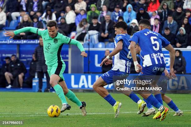 Atletico Madrid's Spanish midfielder Saul Niguez is challenged by Alaves' Spanish defender Andoni Gorosabel and Alaves' Moroccan defender Abdelkabir...