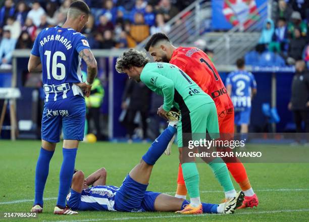 Atletico Madrid's French forward Antoine Griezmann helps Alaves' Argentine forward Giuliano Simeone with a cramp during the Spanish league football...