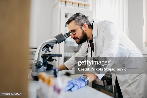 Handsome lab technician using a telescope Handsome lab technician using a telescope