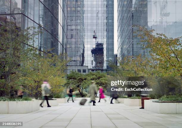 business people and office workers passing square at modern business district at dawn - büropark stock-fotos und bilder