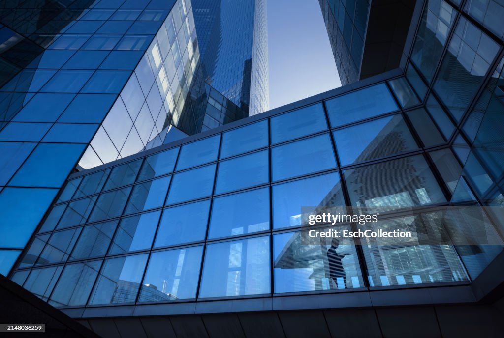Modern office buildings with silhouette of businessman crossing elevated overpass