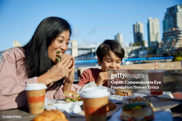 asian family enjoying lunch on day out in city - woman eating bagel stock pictures, royalty-free photos & images