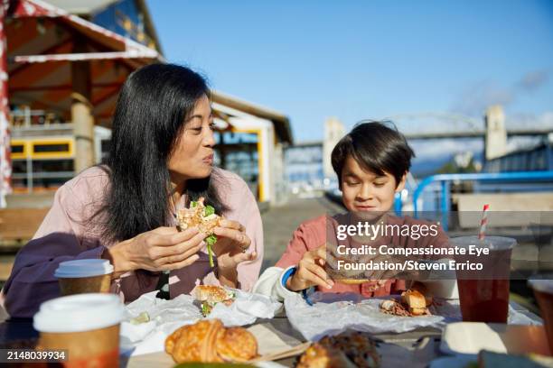 chinese mother and son enjoying lunch in city - woman eating bagel stock pictures, royalty-free photos & images