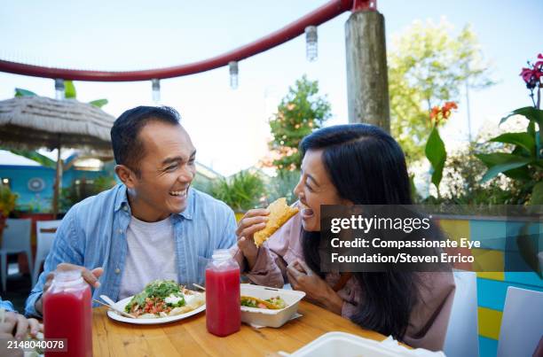 happy asian couple eating tacos in outdoor restaurant - couple eating stock pictures, royalty-free photos & images
