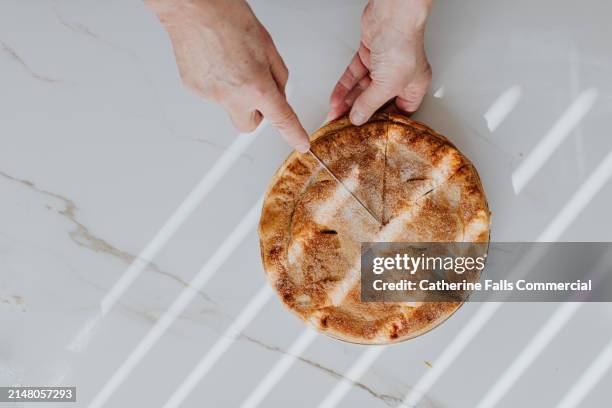 top down image of a person cutting into an apple pie - pie stockfoto's en -beelden
