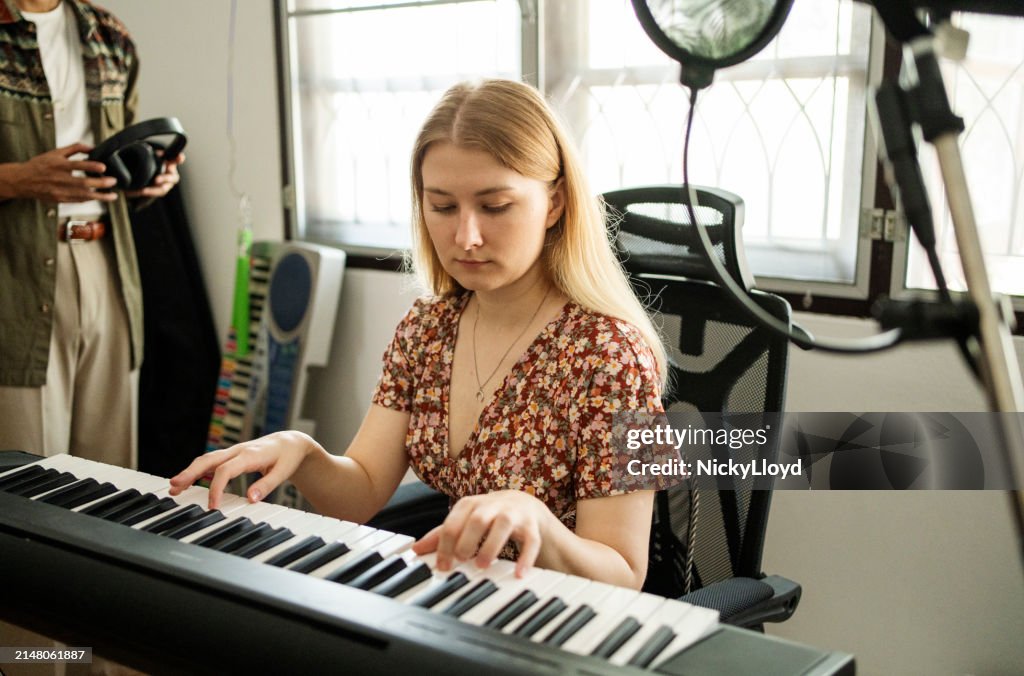 Young woman playing the keyboards in a home music studio