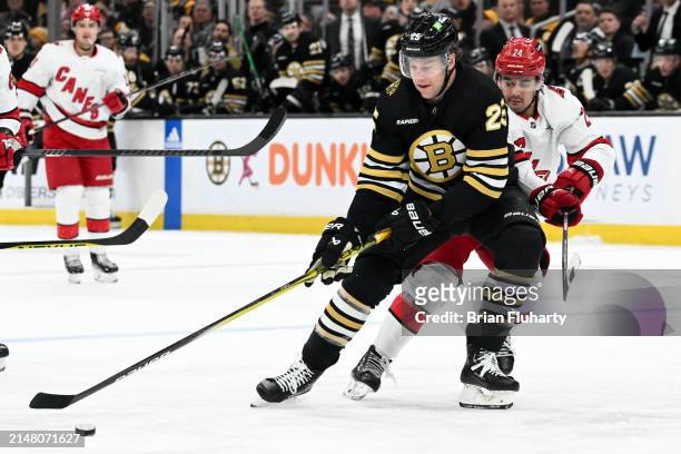 Brandon Carlo of the Boston Bruins controls the puck against Seth Jarvis of the Carolina Hurricanes during the first period at the TD Garden on April...