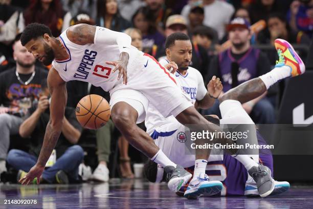 Paul George of the LA Clippers controls the ball after Norman Powell and Royce O'Neale of the Phoenix Suns collide during the second half of the NBA...