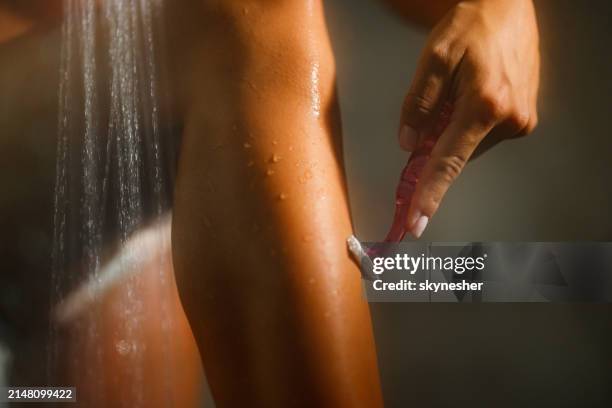 woman shaving her leg in the bathroom. - scheren stockfoto's en -beelden