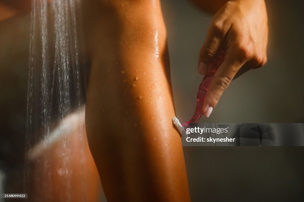 Woman shaving her leg in the bathroom.