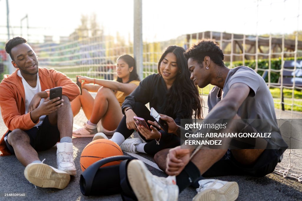 Urban basketball players using phone and chatting on the court