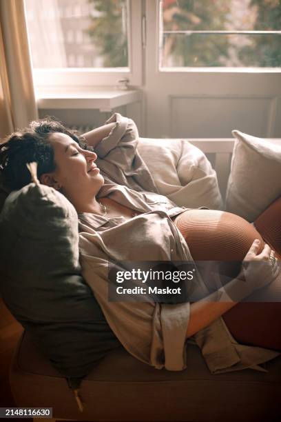 high angle view of pregnant woman relaxing on sofa at home - être enceinte photos et images de collection