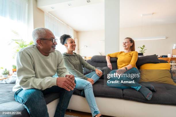 diverse family enjoying conversation indoors - adult offspring stock pictures, royalty-free photos & images