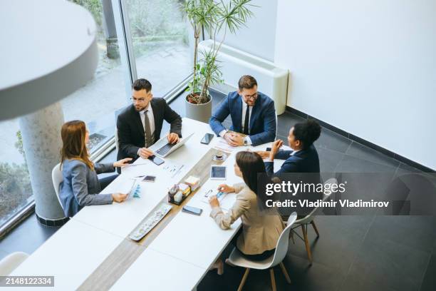 team working around a conference table - vestuário de trabalho formal imagens e fotografias de stock