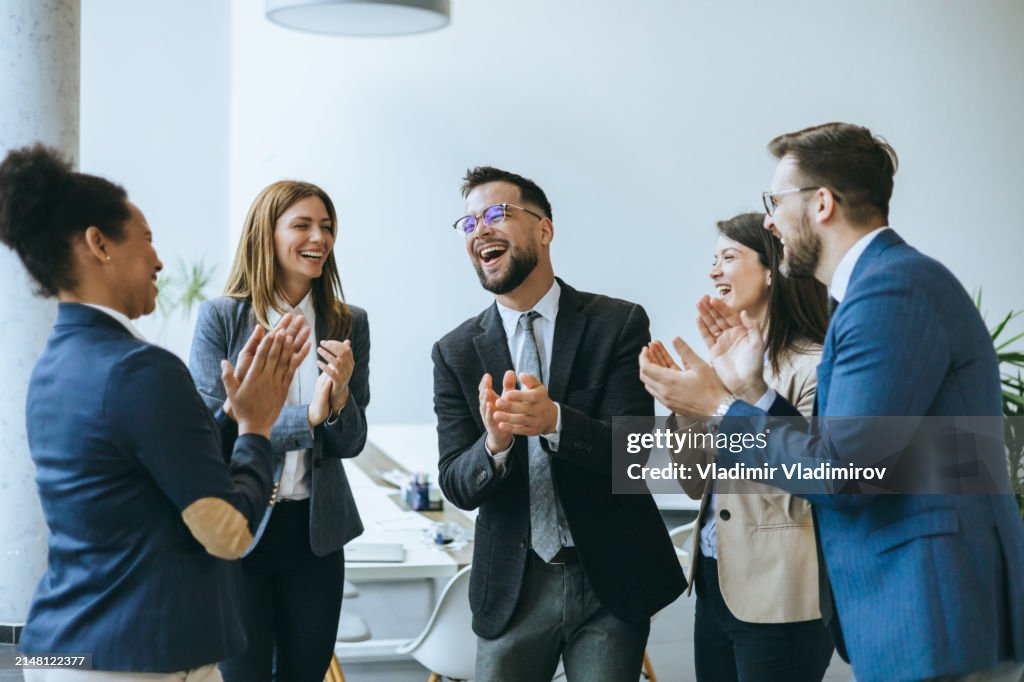 Office team applauding a happy colleague