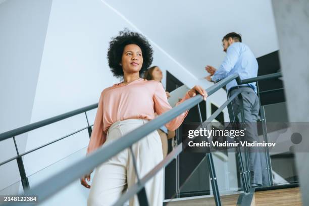 businesswoman going the stairs down in office - round table discussion women stock pictures, royalty-free photos & images