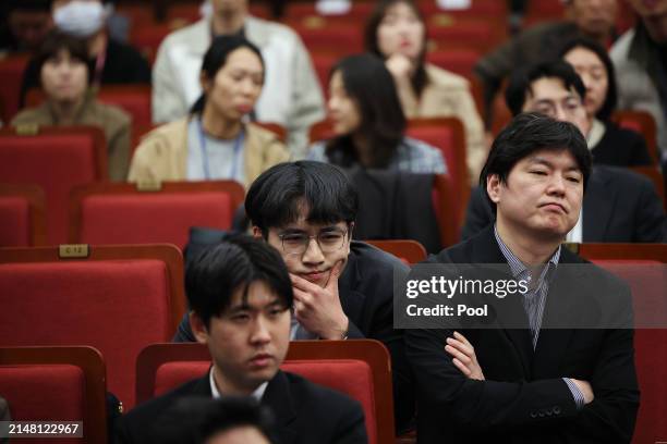 Staff of the South Korean ruling People Power Party react as they watch a news report on the results of exit polls for parliamentary election at the...