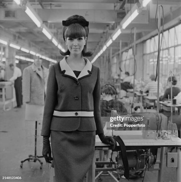 Female fashion model posed wearing a single breasted jacket with matching pencil skirt, the jacket has a contrasting collar and horizontal stripe...