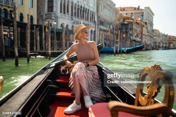 woman on a gondola tour sailing in grand canal in venice, italy - europe travel stock-fotos und bilder