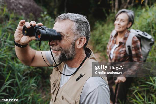 elderly man observing nature with binoculars - bird watching stock pictures, royalty-free photos & images